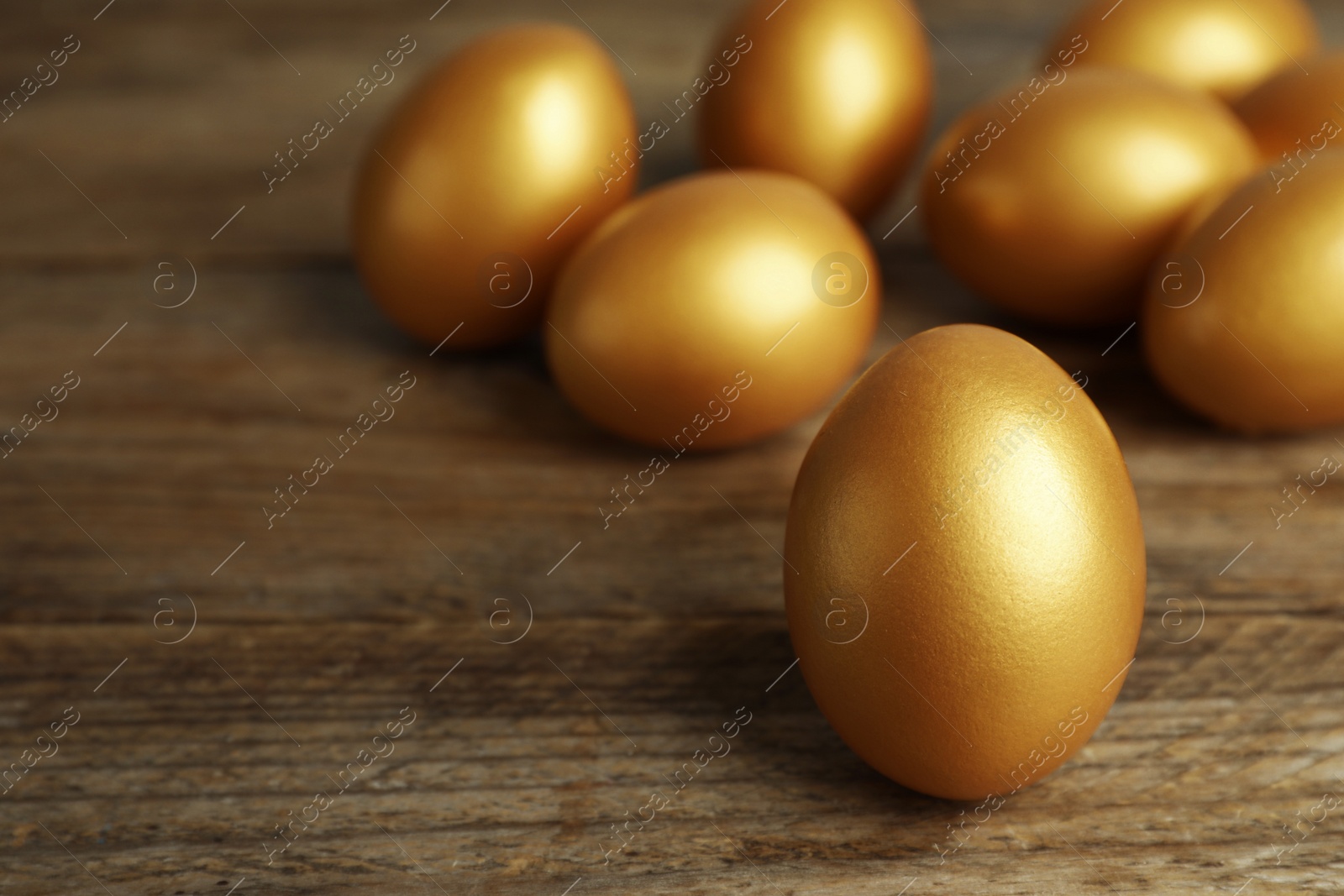 Photo of Many golden eggs on wooden table, closeup. Space for text