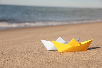 Photo of Color paper boats near sea on sandy beach
