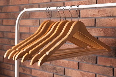 Photo of Wooden clothes hangers on rack near red brick wall