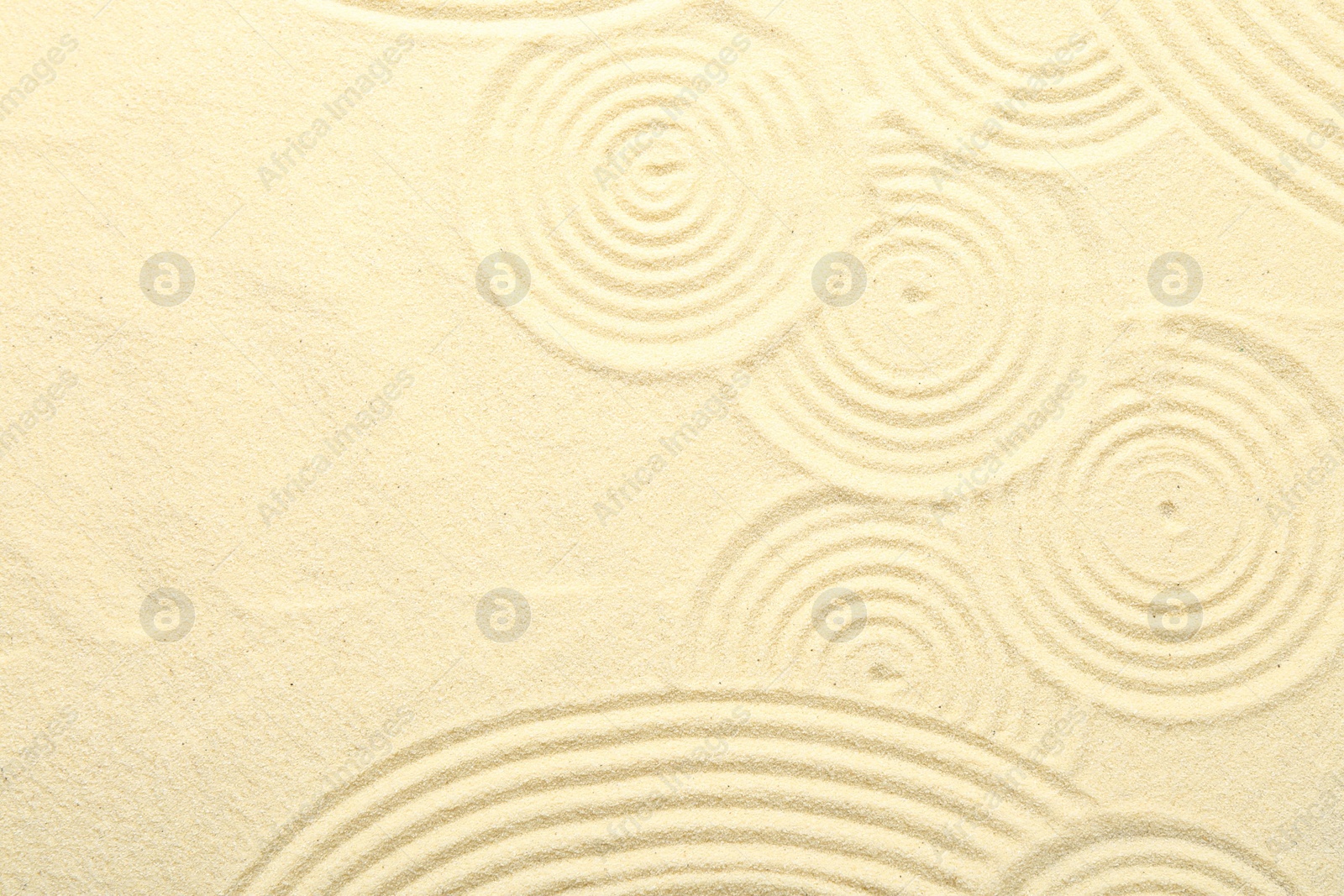 Photo of Zen rock garden. Circle patterns on beige sand, top view