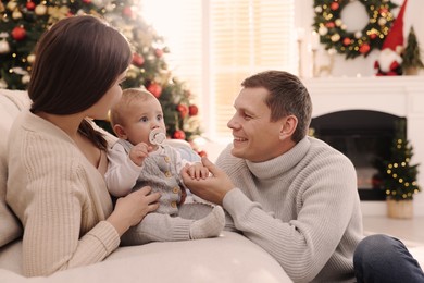 Photo of Happy couple with cute baby in living room decorated for Christmas
