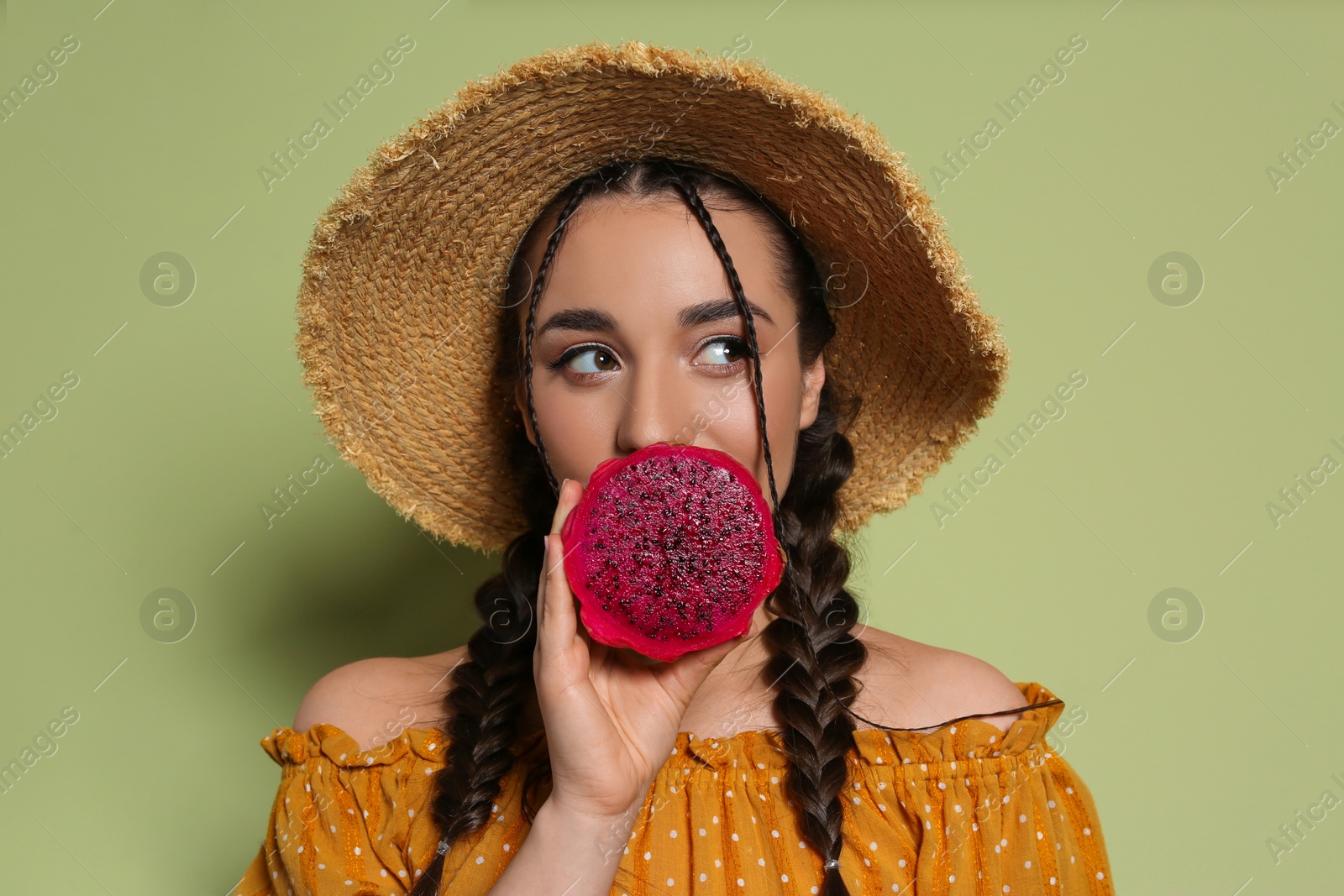 Photo of Young woman with fresh pitahaya on olive background. Exotic fruit