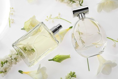Luxury perfumes on spring floral decor, top view
