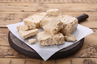 Photo of Pieces of tasty halva on wooden table