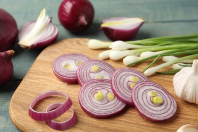 Photo of Cut red onion on wooden board, closeup