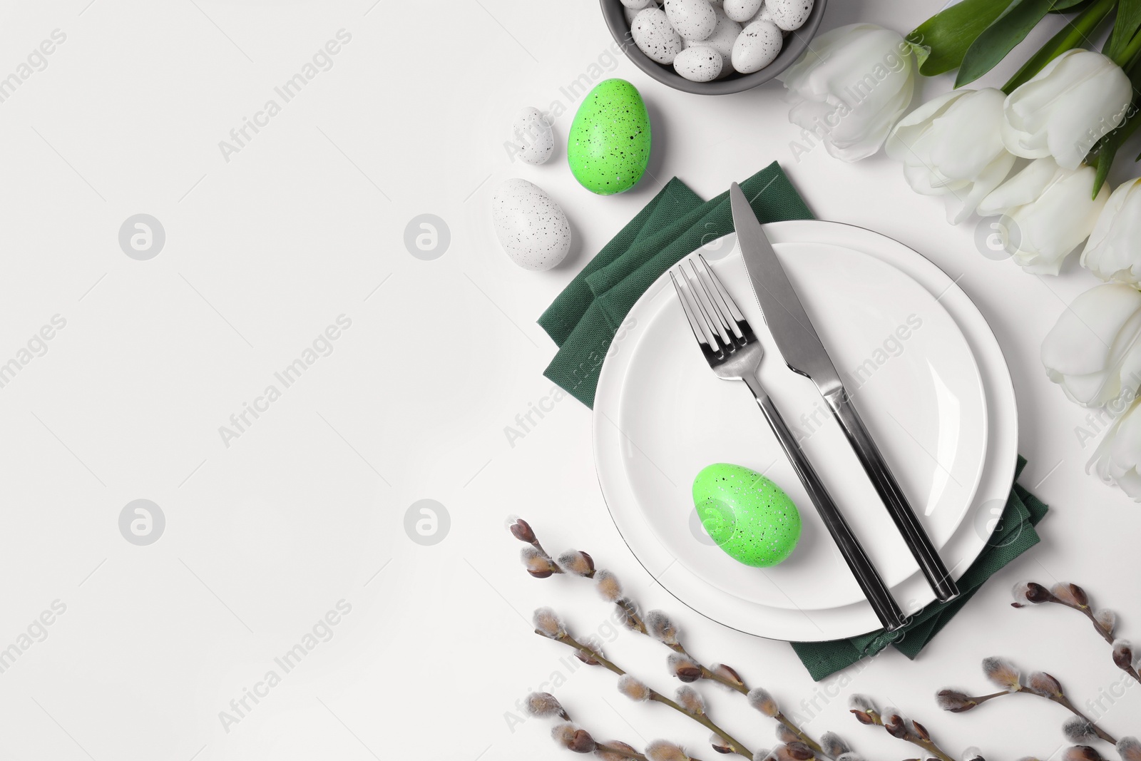 Photo of Festive table setting with tulips and willow twigs on white background, flat lay with space for text. Easter celebration