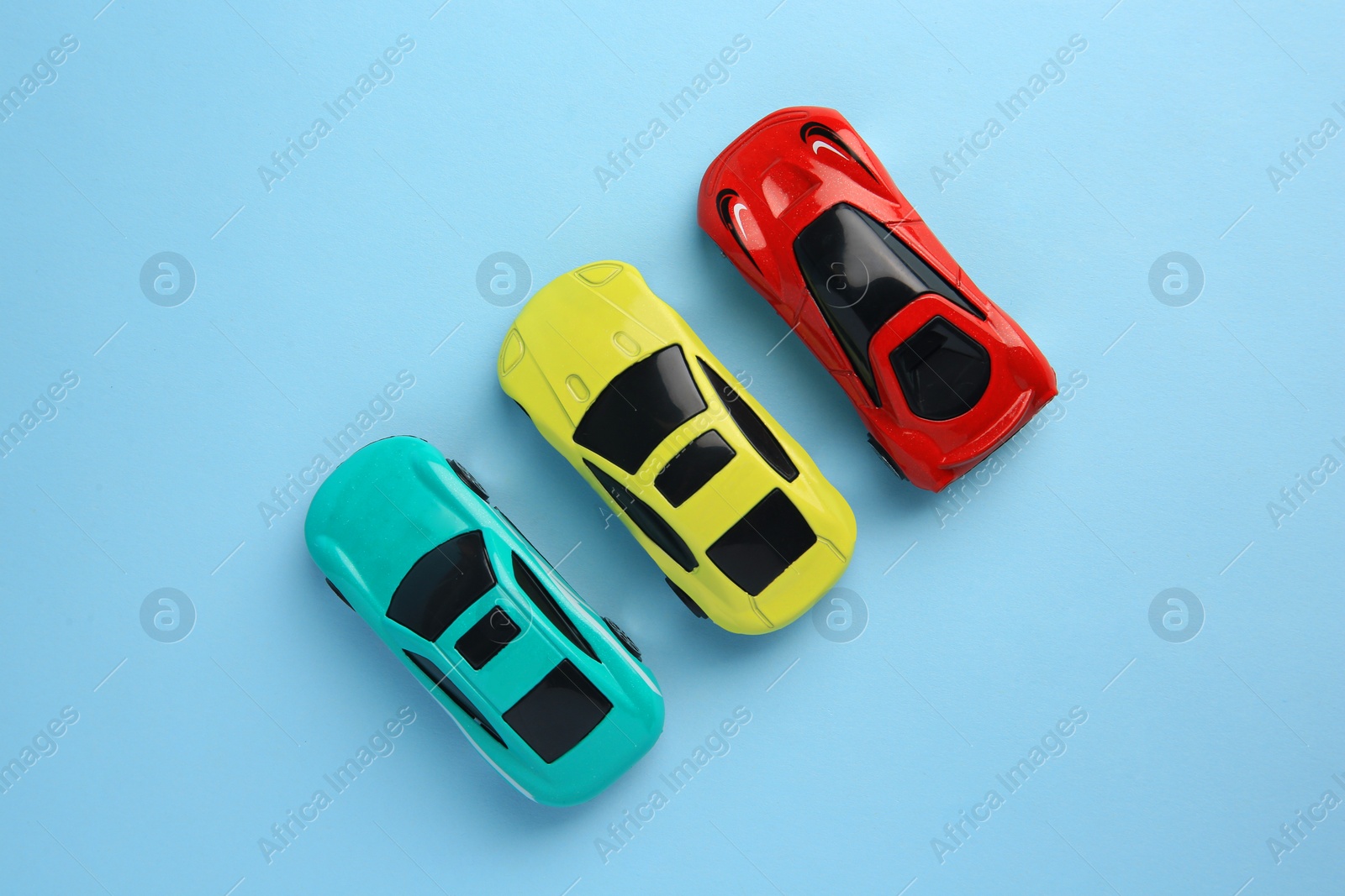 Photo of Different bright cars on light blue background, flat lay. Children`s toys