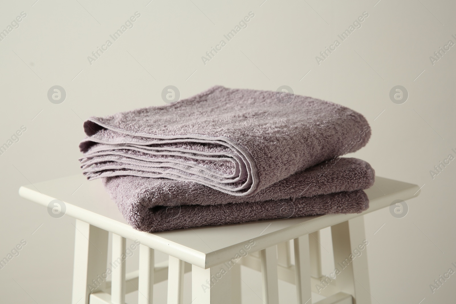 Photo of Violet towels on stool against white wall, closeup