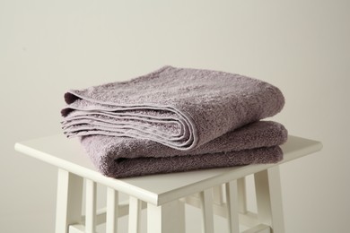 Violet towels on stool against white wall, closeup