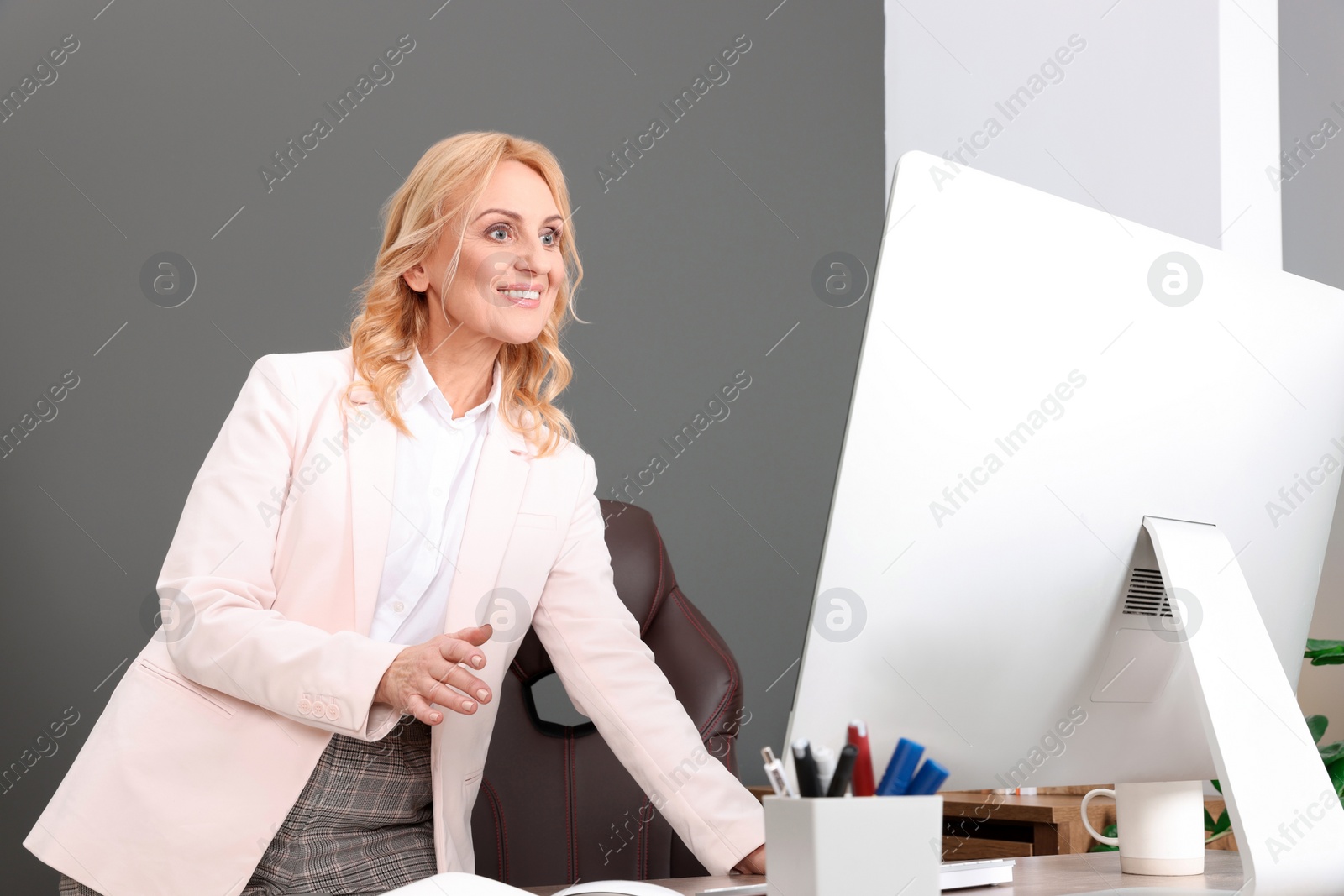 Photo of Happy lady boss working on computer in office. Successful businesswoman