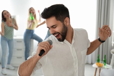 Photo of Young man singing karaoke with friends at home