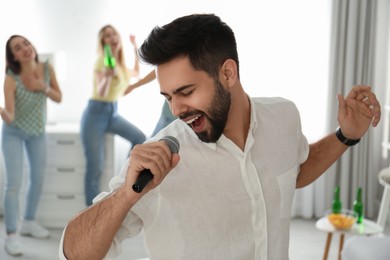 Young man singing karaoke with friends at home