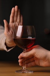 Photo of Woman refusing to drink red wine indoors, closeup. Alcohol addiction treatment