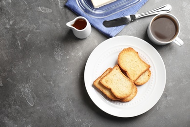 Photo of Plate with toasted bread and cup of coffee on grey background, top view