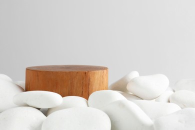 Photo of Presentation for product. Wooden podium and white pebbles on light background. Space for text