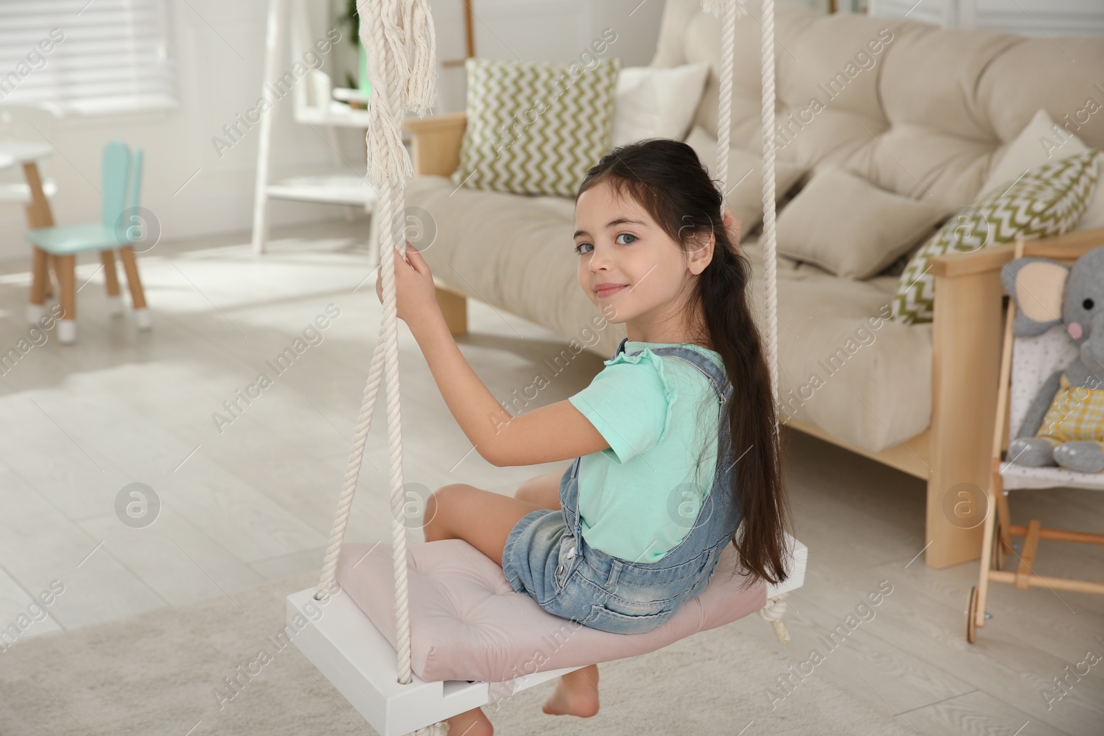 Photo of Cute little girl playing on swing at home