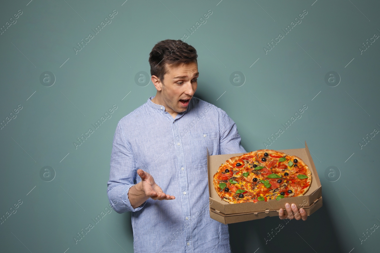 Photo of Attractive young man with delicious pizza on color background