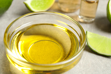 Lime essential oil in bowl on light table, closeup