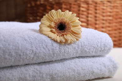 Photo of Stacked terry towels and flower on white table, closeup