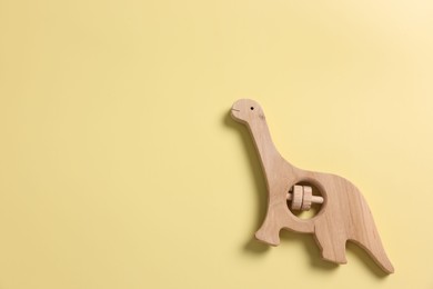 Photo of Baby accessory. Wooden rattle on yellow background, top view. Space for text