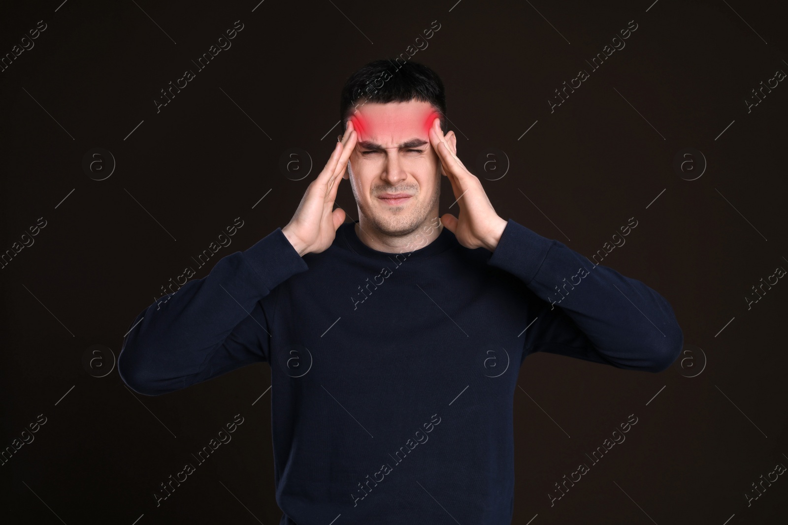 Image of Young man suffering from headache on dark background. Cold symptoms