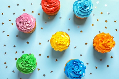 Photo of Flat lay composition with colorful birthday cupcakes on color background