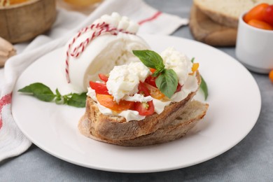 Photo of Delicious sandwich with burrata cheese and tomatoes on grey table, closeup