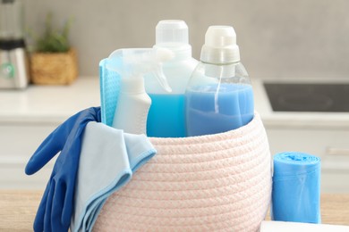 Photo of Different cleaning supplies in basket on table, closeup