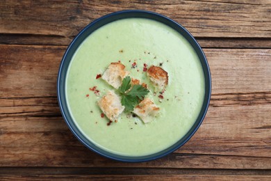 Photo of Delicious asparagus soup with croutons on wooden table, top view