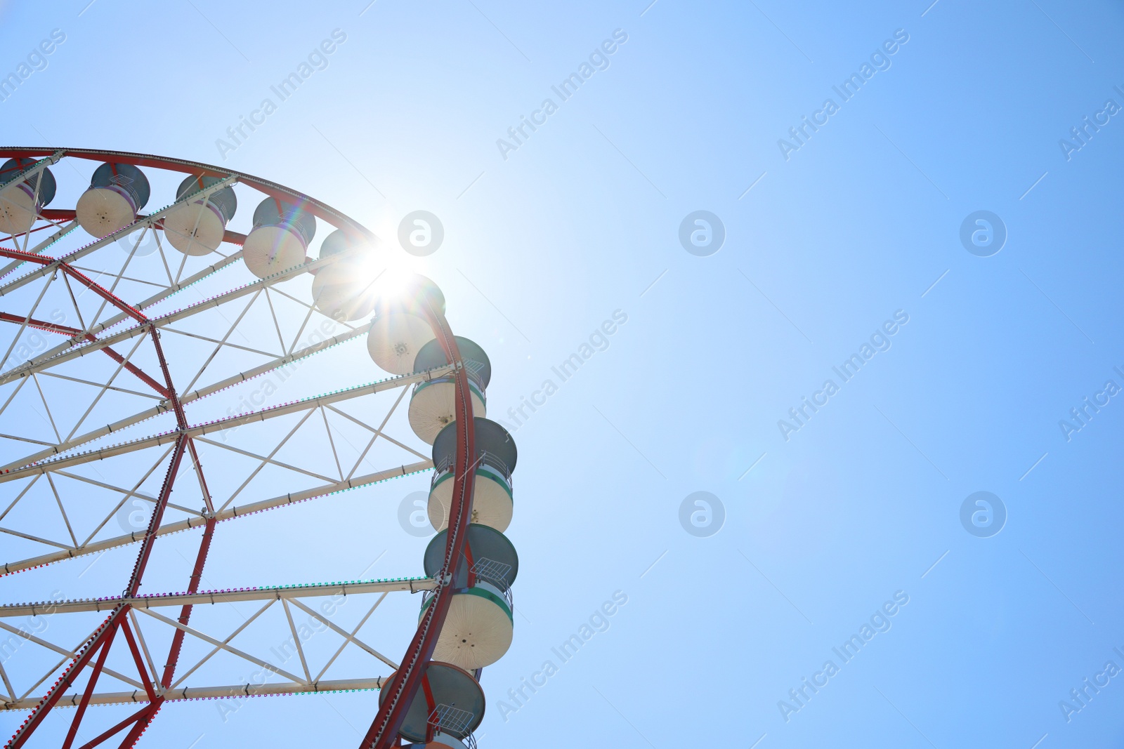 Photo of Beautiful Ferris wheel against blue sky on sunny day, low angle view