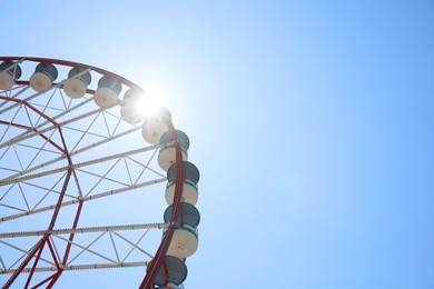 Photo of Beautiful Ferris wheel against blue sky on sunny day, low angle view