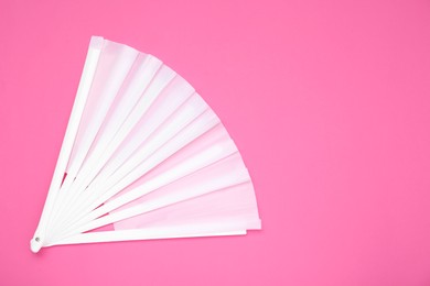 Stylish white hand fan on pink background, top view. Space for text