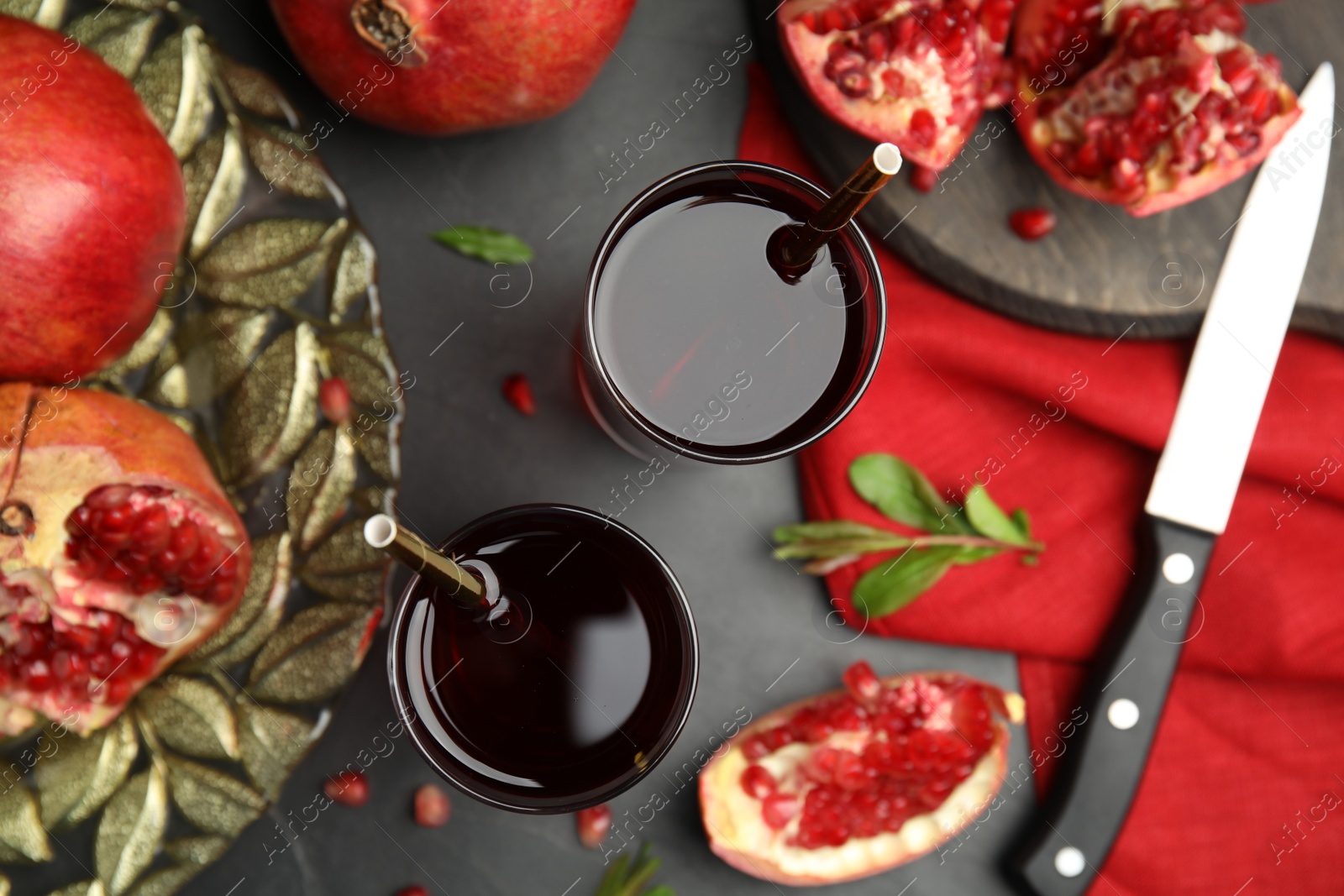 Photo of Glasses of pomegranate juice and fresh fruits on black table, flat lay