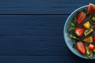 Photo of Food photography. Delicious fresh fruits and mint leaves on blue wooden table, top view with space for text