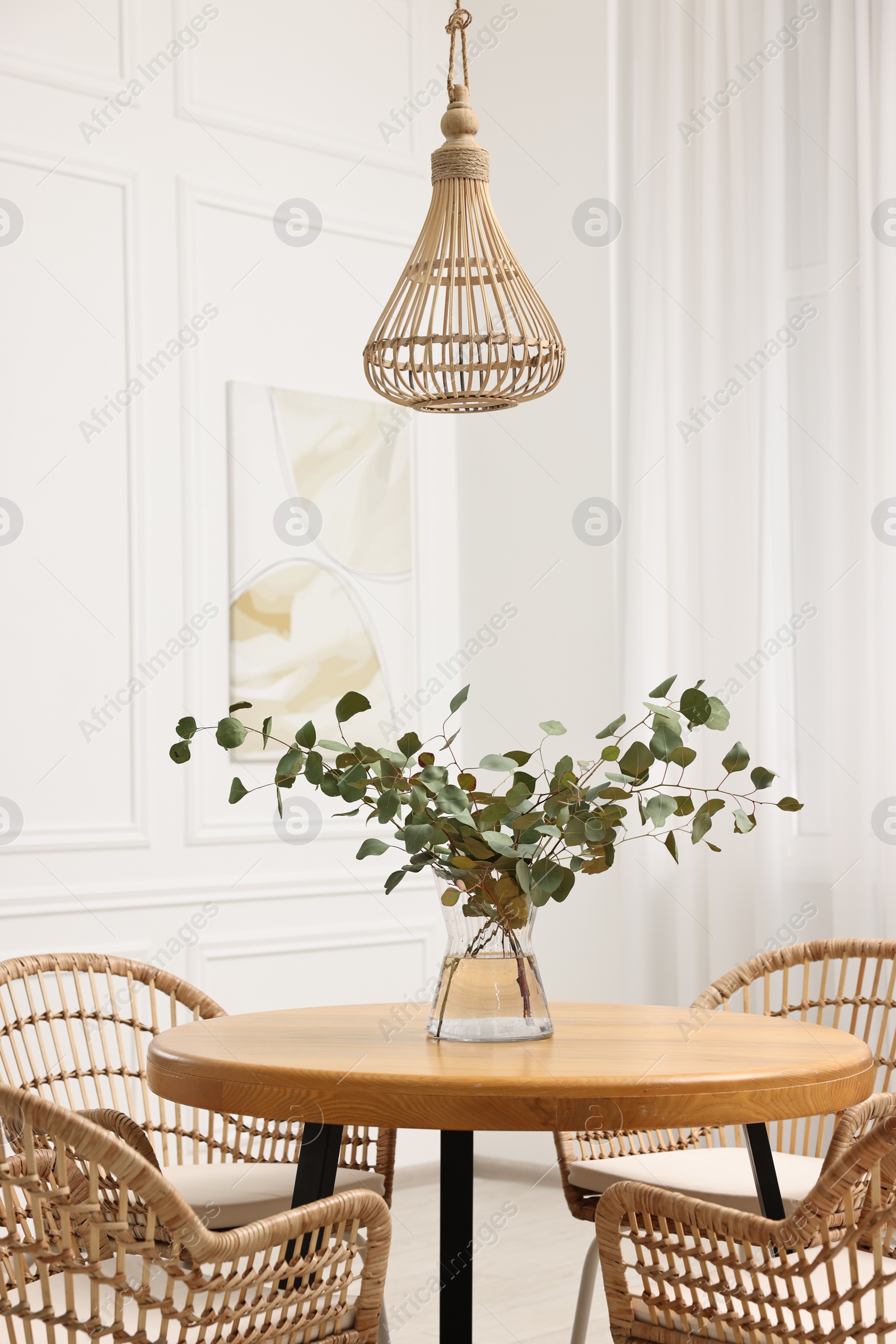 Photo of Dining room interior with comfortable furniture and eucalyptus branches