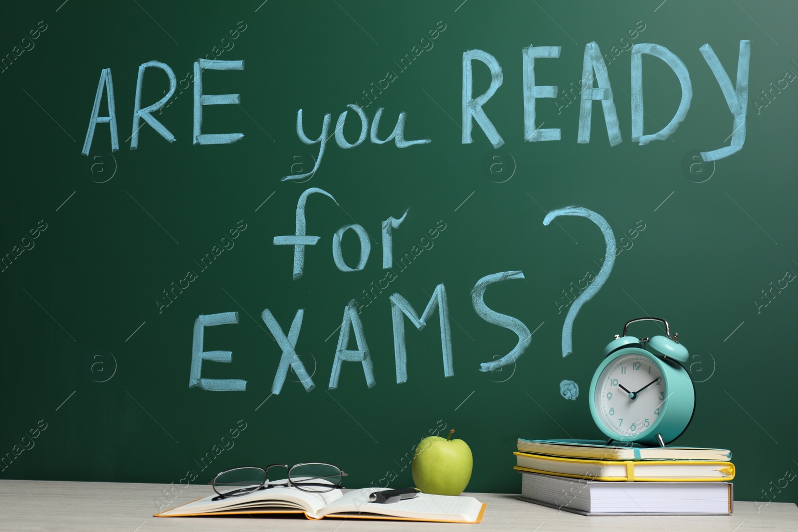 Photo of Different stationery and alarm clock on wooden table near chalkboard with phrase Are You Ready For Exams