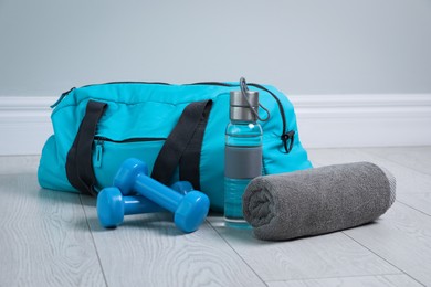 Photo of Bag with different sports equipment on wooden floor indoors