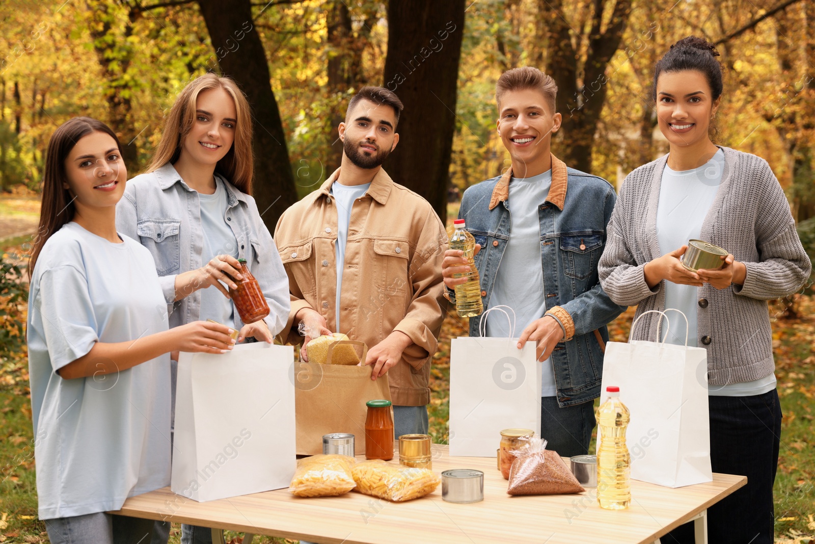 Photo of Portrait of volunteers packing food products at table in park