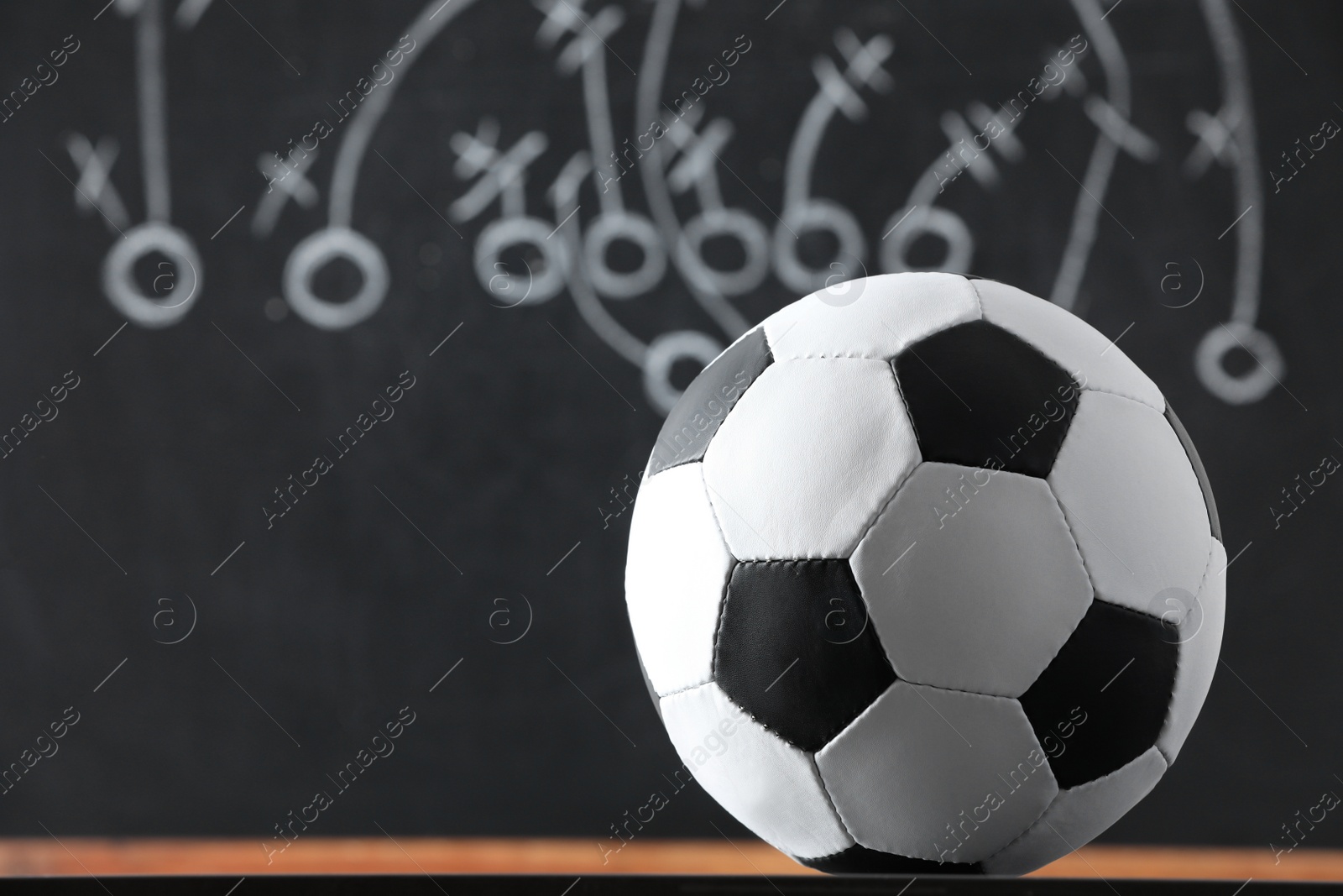 Photo of Football ball against blurred game scheme. Space for text