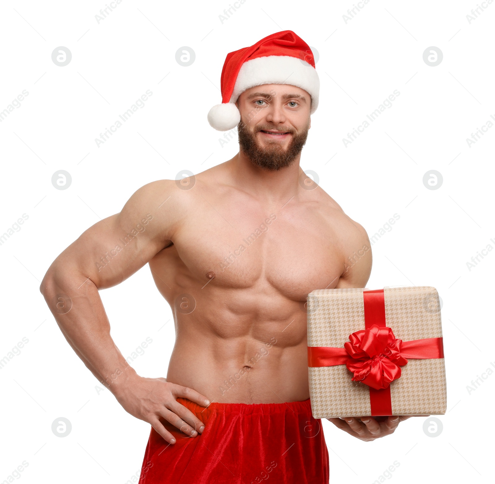 Photo of Attractive young man with muscular body in Santa hat holding Christmas gift box on white background