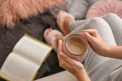 Photo of Woman with cup of hot coffee resting at home, above view. Space for text