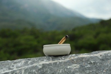 Photo of Burnt palo santo stick on stone surface in high mountains