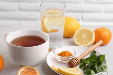 Cup of delicious immunity boosting tea with citrus fruits and turmeric on light grey table