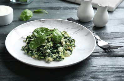 Photo of Tasty cooked spinach served on dark wooden table. Healthy food