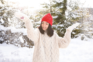 Happy young woman playing with snow outdoors. Winter vacation