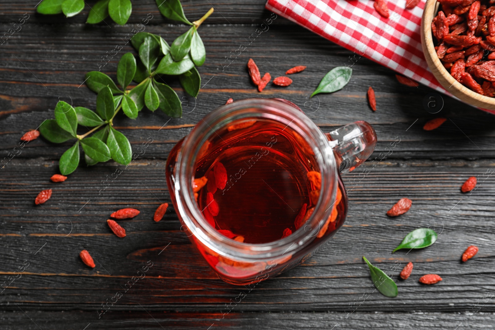 Photo of Healthy goji juice in mason jar on wooden table, flat lay