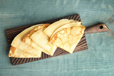 Photo of Fresh thin pancakes on blue wooden table, top view