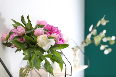 Photo of Shelf with vase of beautiful peonies on white wall. Space for text