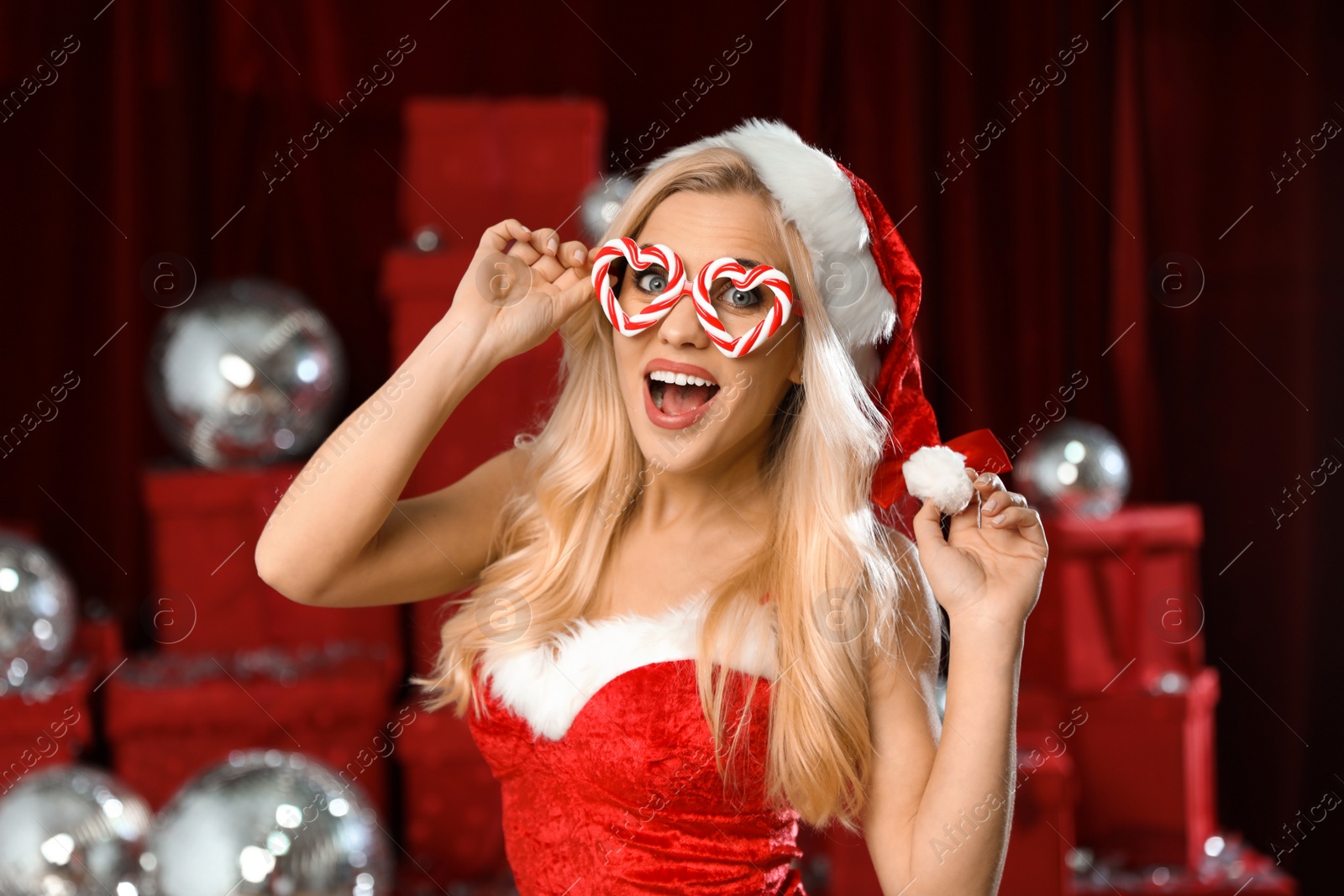 Photo of Beautiful woman in Christmas costume near pile of presents indoors