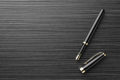 Photo of Stylish fountain pen on black wooden table, top view. Space for text